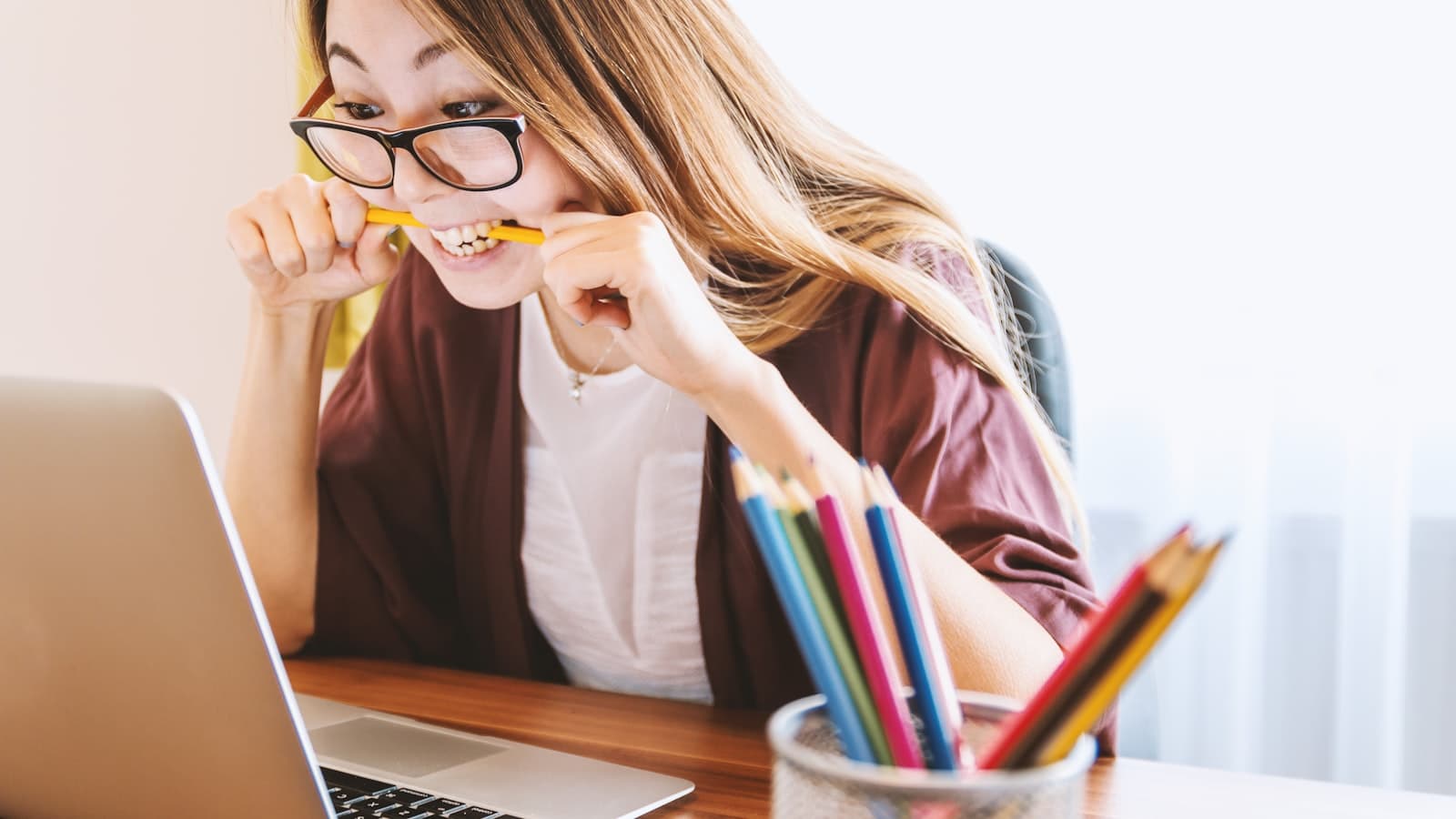 Creator sitting at a desk with a laptop and a pot of colored pencils, thinking through video ideas
