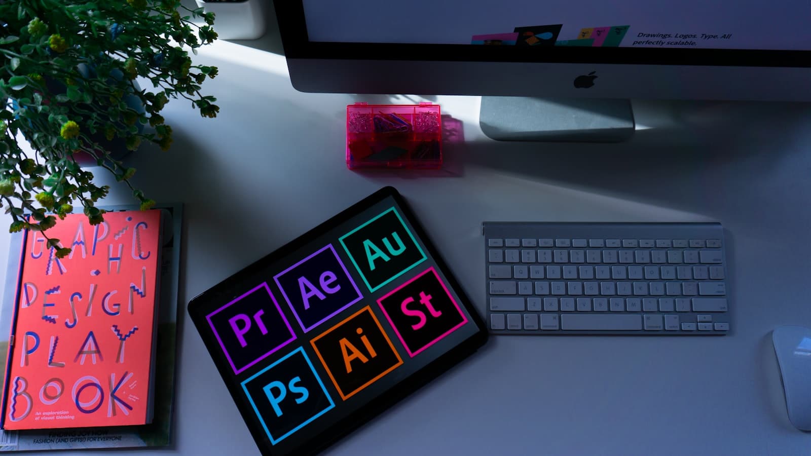 Design workspace with Adobe Creative Cloud shortcut keys, a design playbook notebook and a keyboard