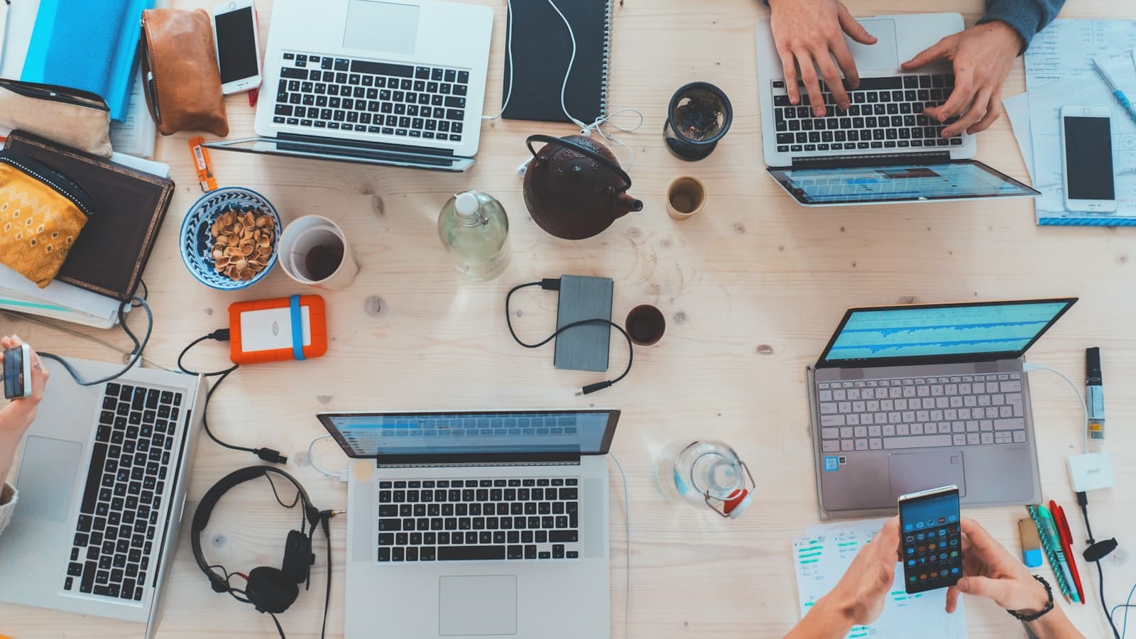 Overhead view of a desk with laptops, notebooks and coffee cups during a data review session