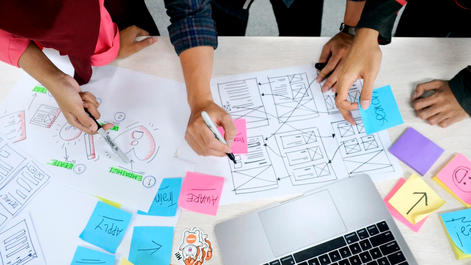 Team gathered around a table sketching a content plan on paper with colored sticky notes