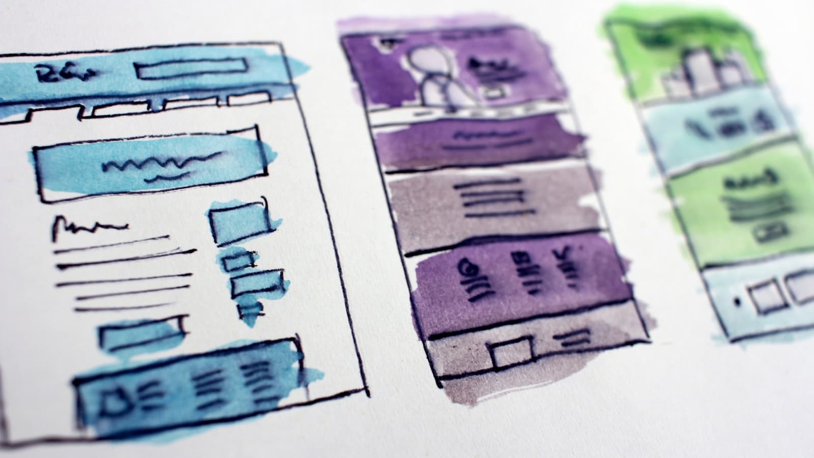 Hand-drawn wireframe sketches of layout compositions on paper in purple and green marker