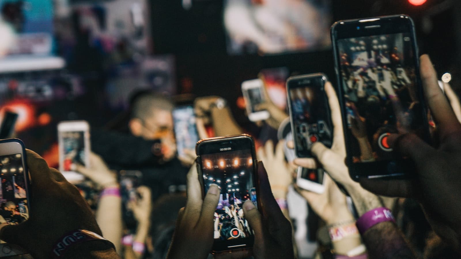 Crowd of people holding smartphones up in the air filming an event in vertical format