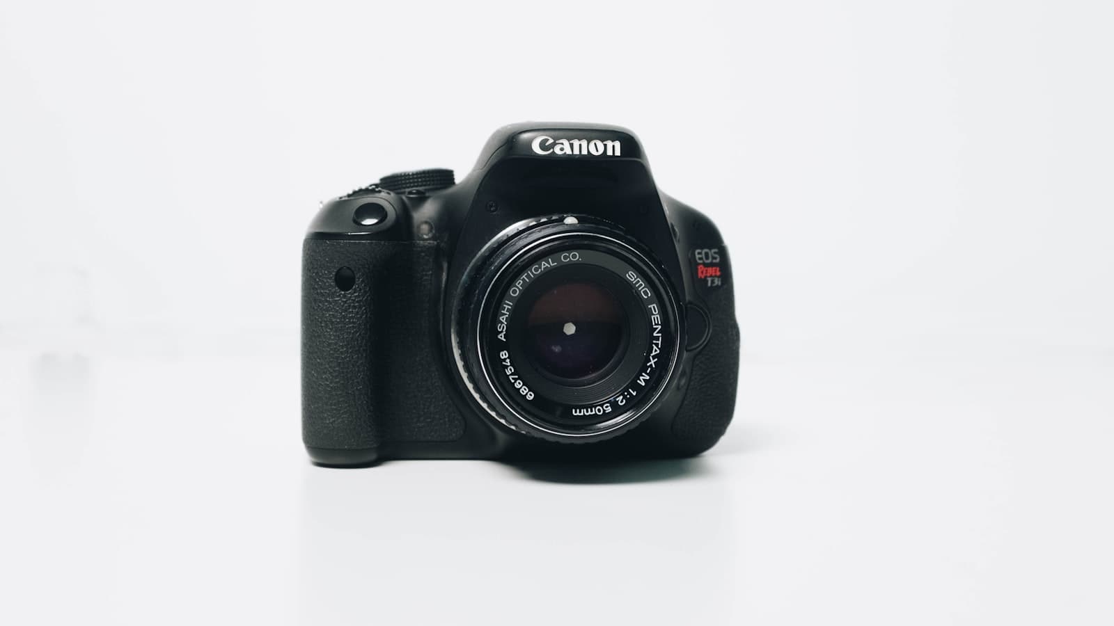 Black DSLR camera with a zoom lens photographed against a plain white background